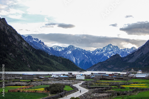Bild auf Leinwand Beautiful mountainous landscape with snow-capped peaks and green fields