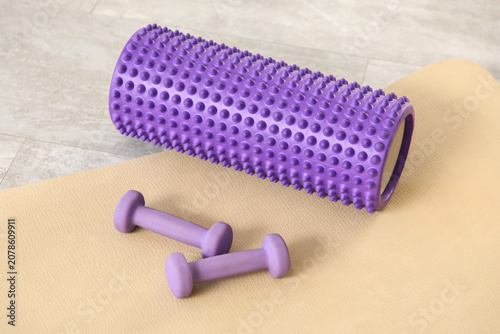 Bild auf Leinwand Purple foam roller and dumbbells on beige yoga mat