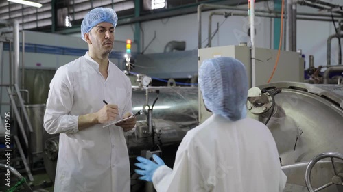 Food industry engineers examining large sterilization tank equipment in plant
