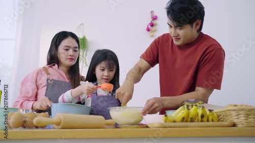 Happy Asian family mixing flour dough together to bake dessert in kitchen