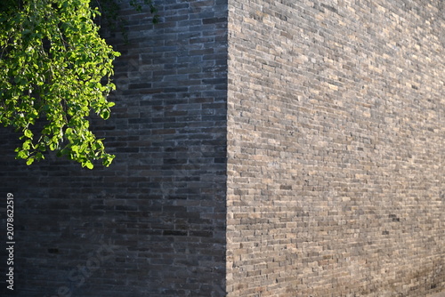 Fotografía A corner of an ancient city wall stands divided—one side bathed in warm sunlight, the other cloaked in cool shadow, embodying time’s quiet duality