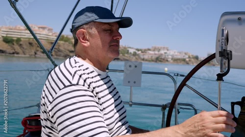 Experienced male skipper steering sailboat at sea