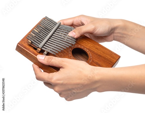 A person's hands holding a small, wooden musical instrument with metal keys