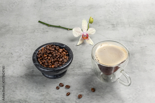 Stone bowl with roasted coffee beans and a cup of coffee.