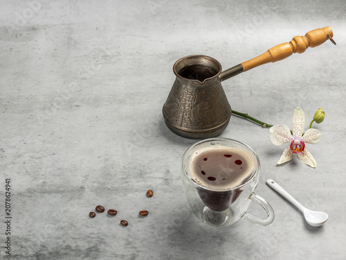 Cup of coffee, a cezve and an orchid flower.