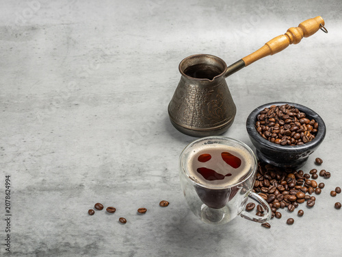 Cup of coffee, a stone bowl with roasted coffee beans and a cezve.