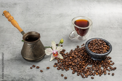Cezve, a cup of coffee and a stone bowl with roasted coffee beans.