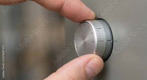 Hand carefully adjusting a metallic control dial on a modern device