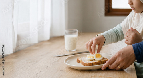 Muslim girl wearing hijab eating healthy breakfast with boiled egg and bread