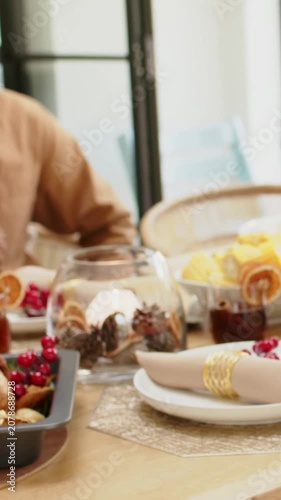 Vertical video: Panning camera left across dining table, family sharing roasted bird, child red top