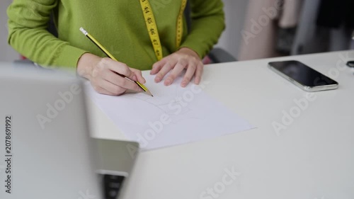 Fashion designer drawing sketches on paper at desk