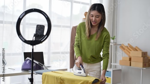 Young asian woman ironing clothes and recording a video tutorial