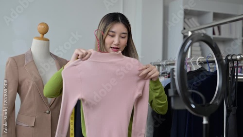 Fashion designer presenting pink sweater in online video