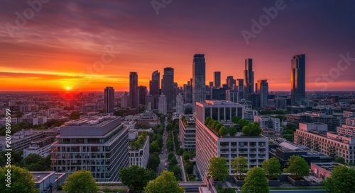 Vibrant sunset over a modern city skyline with skyscrapers and green spaces.