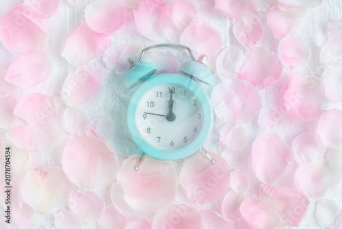 Canvastavla Pastel blue alarm clock with its hands indicating midnight or midday, lying amon