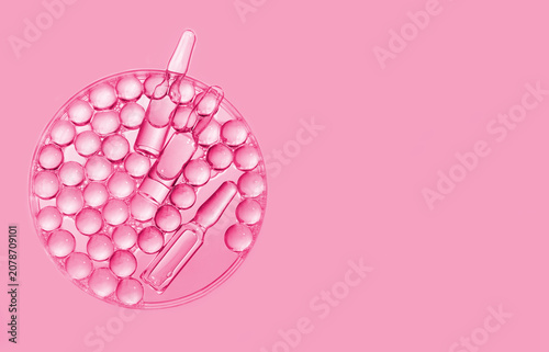 Medical ampoules and gel granules in Petri dish, pink background. Laboratory cosmetology, biotechnology, anti-aging skincare, scientific innovations
