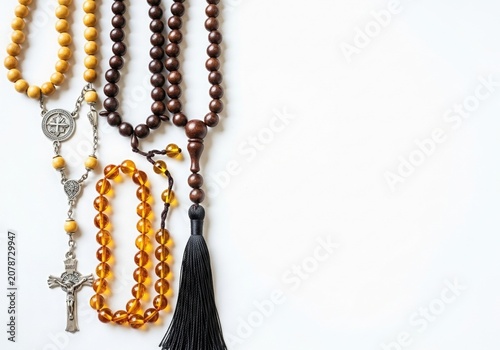 Rosary beads and prayer necklaces with wooden and amber beads arranged on a white background with generous copy space symbolizing faith spirituality devotion and religious traditions