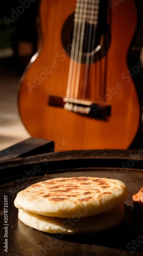 Arepas on cast-iron griddle beside cuatro guitar, tropical culinary and music scene.
