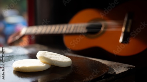 Arepas on cast-iron griddle beside cuatro guitar, tropical culinary and music scene.
