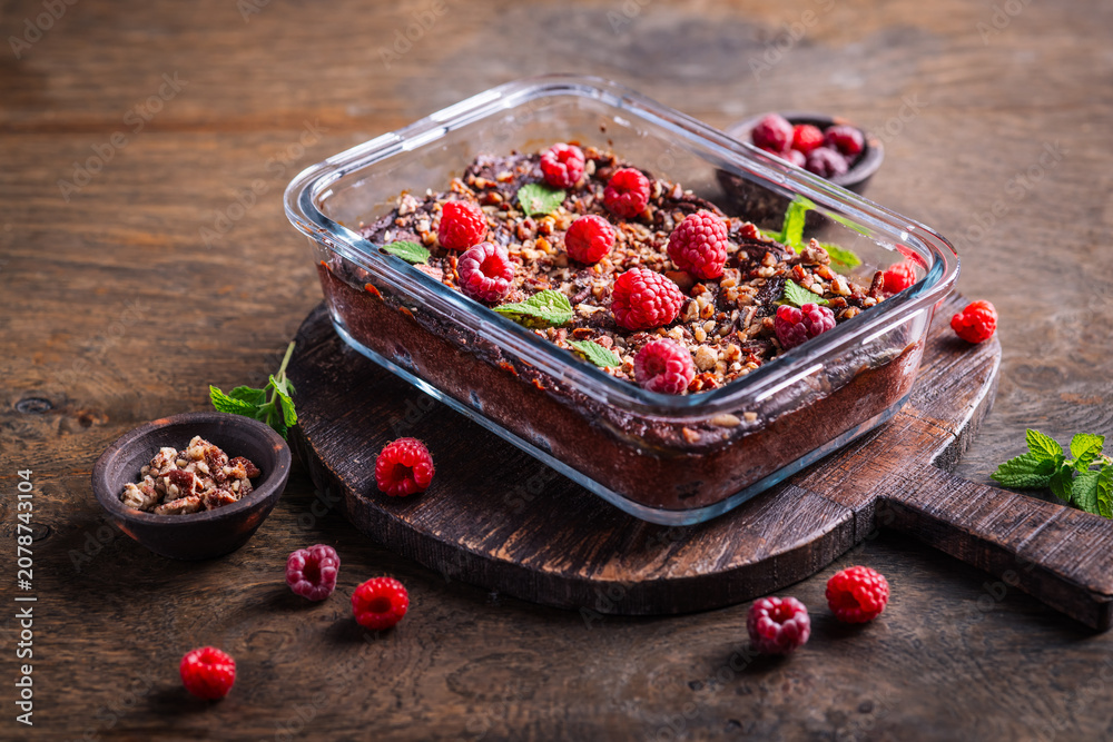 Fototapeta premium Decadent chocolate raspberry brownie baked in glass dish, topped with nuts and mint