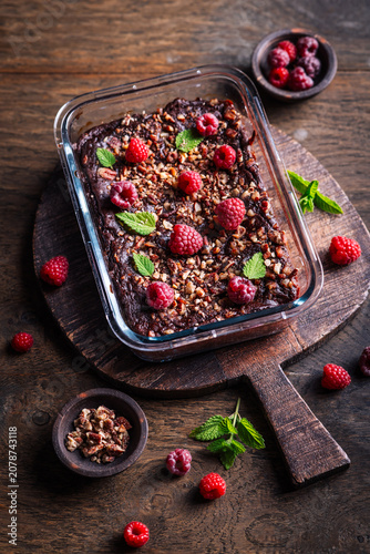 Canvas Print Decadent chocolate raspberry brownie baked in glass dish, topped with nuts and m