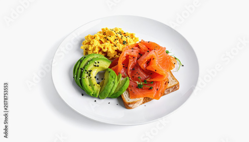 Savory breakfast plate with scrambled eggs, smoked salmon on toast, and sliced avocado with sesame seeds