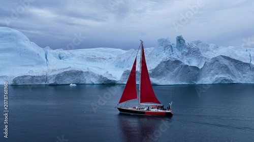 Red sailboat explores a majestic icy landscape