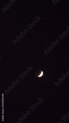 Blood crescent moon Lunar Eclipse on black background in the dark night sky vertical video