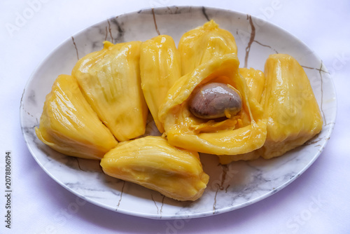Fresh Ripe sweet Jackfruit pods Segments on White Plate, golden juicy and naturally ripe tropical Fruit with seeds, isolated on white background.