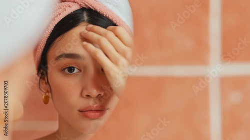 Calm woman with towel wrapped hair in modern bathroom relaxing after skincare routine