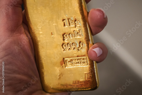 Gold bullion kilo bar in hand. Large cast investment gold ingot. Business and finance.