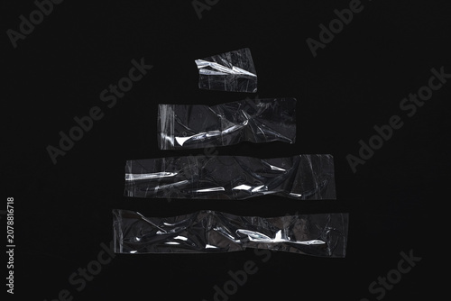 Fotografija Pieces of transparent plastic film on black background