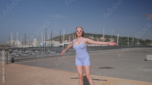 Happy young woman rollerblading along a sunny seaside promenade