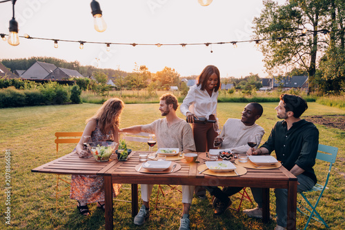 Diverse friends enjoying outdoor dinner party at sunset