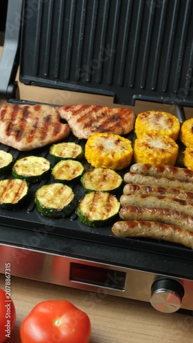 Electric grill with assorted meat and vegetables.