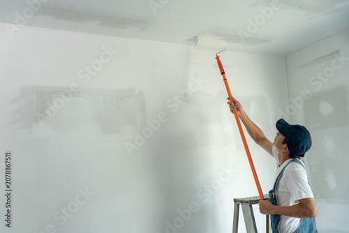 Obraz na plátně painter man, brush in hand for products to restore and paint the wall, indoor th