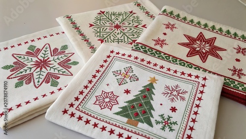 Flat lay of beautifully crafted embroidered Christmas textiles displaying intricate holiday designs in festive colors