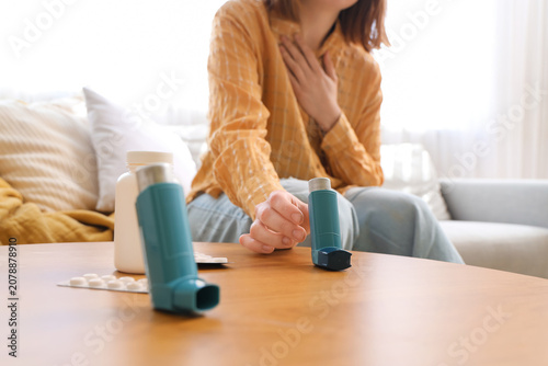 Tableau sur toile Woman with asthma attack taking modern inhaler from coffee table in living room