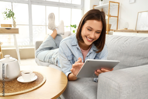 Young woman using tablet computer on sofa at home