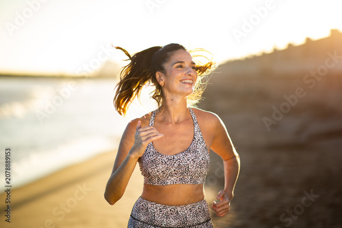 Happy woman running on beach at sunrise