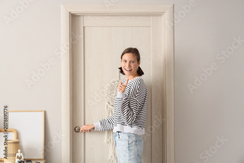Young woman opening door in...
