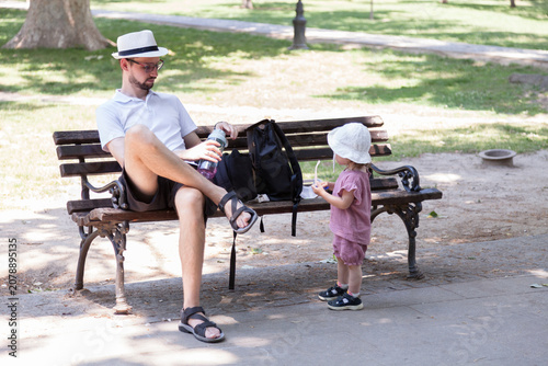 Fotografía Father talking with his toddler daughter beside a park bench