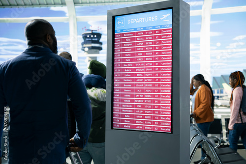 Cuadro en lienzo Unhappy international travelers expressing anxiety after all flights cancellation, disruption of travel plans shown on information board