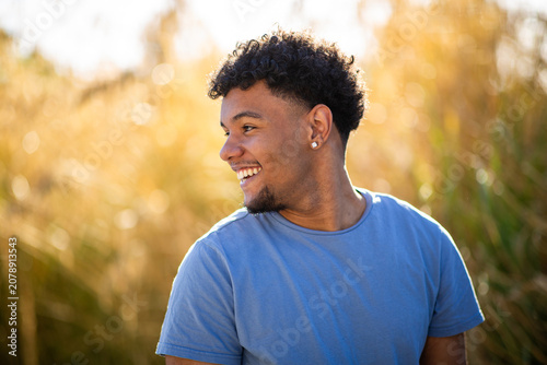 Young man smiling and looking away at sunset