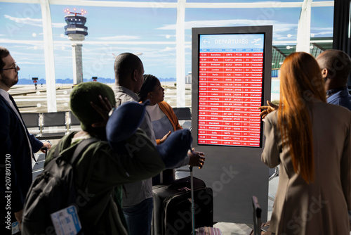 Foto Unhappy international travelers expressing anxiety after all flights cancellation, disruption of travel plans shown on information board
