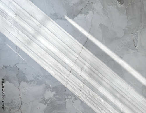 Diagonal Light Rays on Textured Gray Concrete Surface.