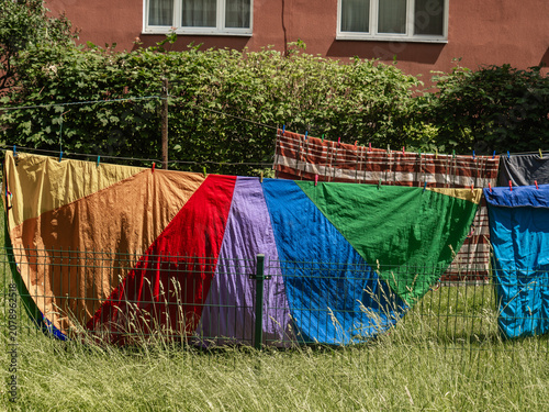 colorful laundry on the lawn of the backyard in the garden.  rainbow blanket in the foreground