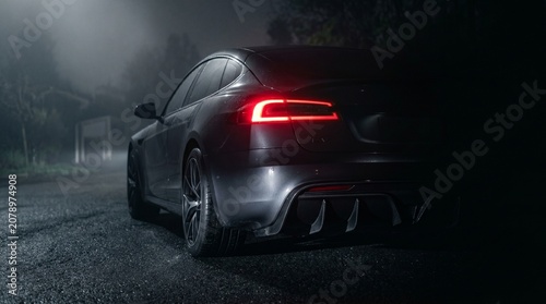 Sleek Black Luxury Sports Car Driving on Empty Road at Dusk