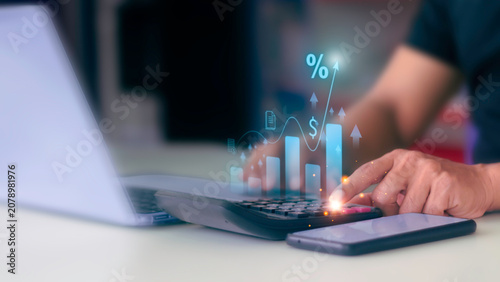 Businessman using calculator with virtual financial growth graph and interest rate percentage icon.