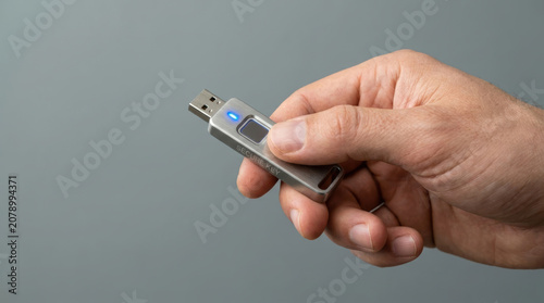 USB flash drive hand holding key data storage digital security portable device technology electronic gadget thumb pressing button gray background